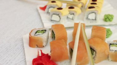 Somon zencefil ve peynir wasabi ve bir kafede beyaz plakalar üzerinde ahşap sopa ile taze lezzetli suşi