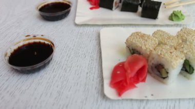 Somon ve balık, pembe zencefil, bir plaka üzerinde yeşil wasabi ve soya sosu güzel şık beyaz arka plan üzerinde suşi ile lezzetli suşi maki