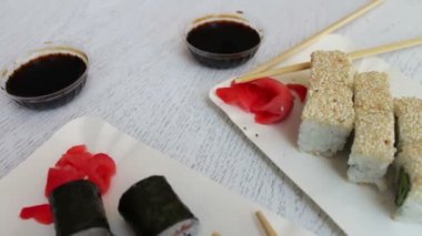 Somon ve balık, pembe zencefil, bir plaka üzerinde yeşil wasabi ve soya sosu güzel şık beyaz arka plan üzerinde suşi ile lezzetli suşi maki