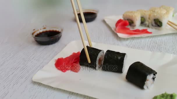 Lahodné sushi-maki se dřevěnými holemi a ponořit se do sójové omáčky, japonské jídlo — Stock video