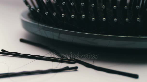 Vrouwen haren kammen, haarborstel met haar extreme macro close-up, in de buurt van zwarte haren clips — Stockvideo