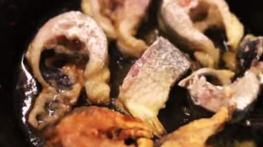 Tatlı su balık bir dökme demir tavada kızartma parçaları.