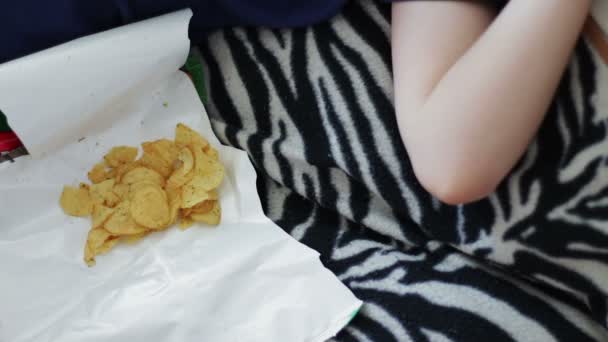 Мальчик ест упаковку картофельных чипсов нездоровой пищи — стоковое видео