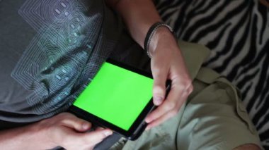 adam yeşil bir ekran ile boş bir tablet Pc kanepede tutar.