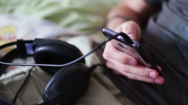 Genç bir akıllı telefon tutarak ve bir ileti yazdırma kanepede yatıyor