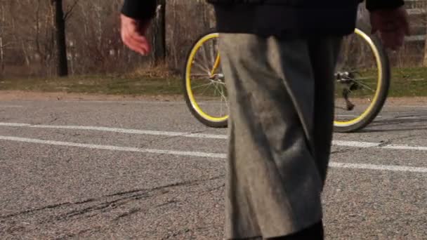 Una donna con una gonna lunga e un ciclista stanno camminando lungo la strada.piedi che camminano sul marciapiede . — Video Stock