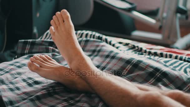 Les jambes de l'homme s'allongent sur le lit, passant du temps libre — Video