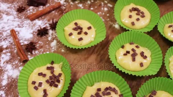 Masa cruda para magdalenas en un plato especial para hornear de papel espolvoreado con trozos de chocolate — Vídeo de stock