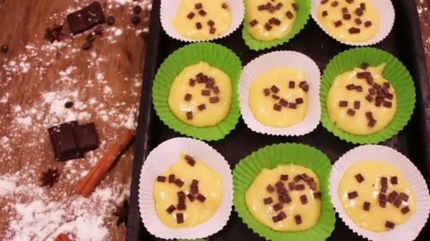 Ruwe deeg voor muffins in speciaal papier bakken schotel besprenkeld met chocoladestukjes — Stockvideo