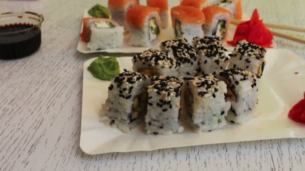 Färsk sushi rullar med lax sesamolja ingefära på en vit bakgrund — Stockvideo