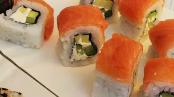 Rollos de sushi fresco con jengibre de sésamo salmón sobre un fondo blanco — Vídeos de Stock