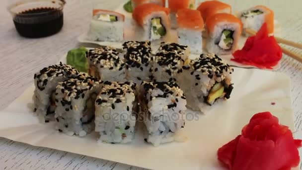 Frische Sushi-Rollen mit Lachs-Sesam-Ingwer auf weißem Hintergrund — Stockvideo