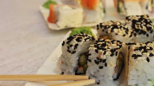 Rolos de sushi frescos com gengibre de gergelim de salmão em um fundo branco — Vídeo de Stock