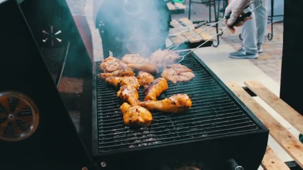 Куряче м'ясо, яке обертається на грилі барбекю. М'ясо смажать на грилі Мангал Барбекю. Куряче м'ясо на грилі під час пікніка — стокове відео