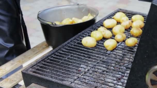 Jeunes pommes de terre fraîches qui sont disposées et retournées sur un barbecue sur le pique-nique — Video