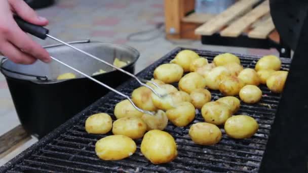Jeunes pommes de terre fraîches qui sont disposées et retournées sur un barbecue sur le pique-nique — Video