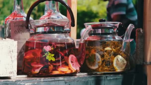 Stylish transparent beautiful teapot with herbal infusion and lemon inside. Street food. Cafe in the open air. Food fair — Stock Video