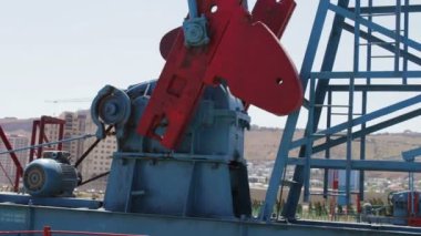Petrol pumpjacks Bakü, Azerbaijan.Silhouette çalışma yağ pompası ve bir eski paslı demir varil yakınındaki bir zemin üzerine mavi gökyüzü ve bulutlar çalışma petrol alanında parçası