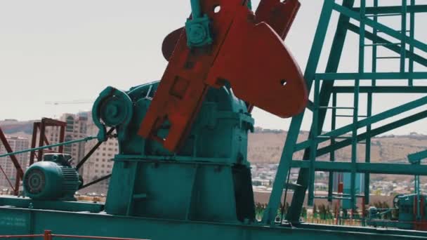 Deel van de olie pumpjacks in een werkende olieveld in Baku, Azerbaijan.Silhouette van werkende oliepomp en een oude roestig ijzer vat in de buurt van op een achtergrond van blauwe lucht en de wolken — Stockvideo