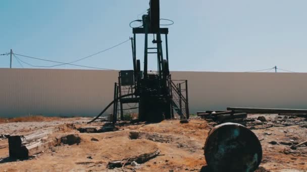 Olja pumpjacks i ett fungerande oljefält i Baku, Azerbaijan.Silhouette av arbetande oljepump och en gammal rostig järn fat nära på en bakgrund av blå himmel och moln — Stockvideo