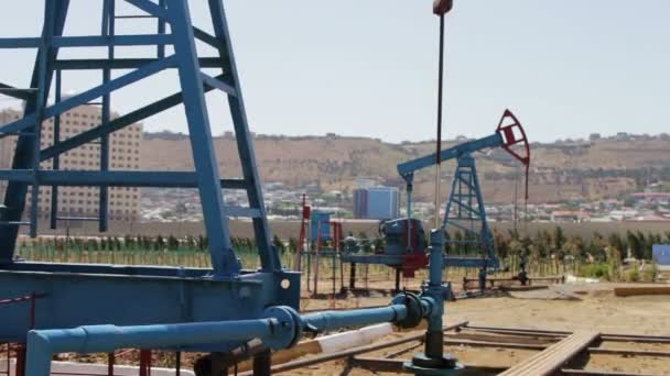Parte de Oil pumpjacks em um campo de petróleo de trabalho em Baku, Azerbaijão. Silhueta de bomba de óleo de trabalho e um velho barril de ferro enferrujado perto em um fundo de céu azul e nuvens — Vídeo de Stock