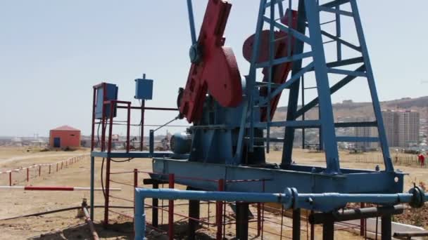Часть нефтяных насосов на действующем нефтяном месторождении в Баку, азербайджан.Силуэт работающего нефтяного насоса и старая ржавая железная бочка рядом на фоне голубого неба и облаков — стоковое видео