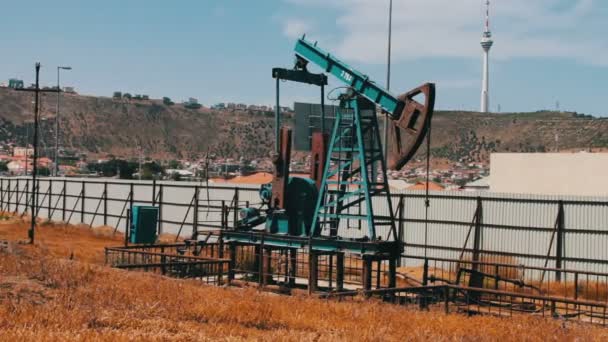 Pracovní olejové čerpadlo a staré rezavé železné barel poblíž na pozadí modré oblohy a mraky. Pumpjacks ropy v práci ropné pole v Baku, Ázerbájdžán. — Stock video