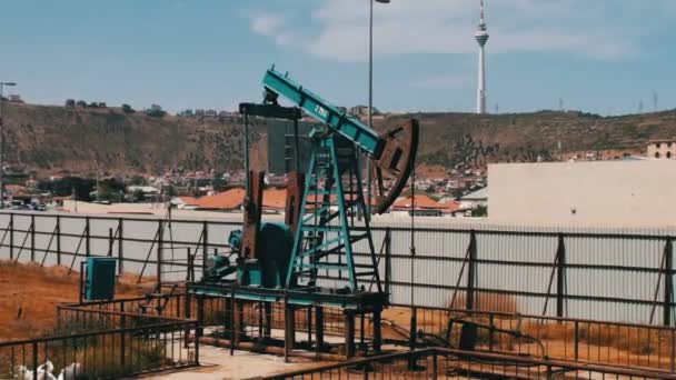 Bomba de aceite de trabajo y un viejo barril de hierro oxidado cerca sobre un fondo de cielo azul y nublas.Bombas de petróleo en un campo petrolero de trabajo en Bakú, Azerbaiyán . — Vídeos de Stock