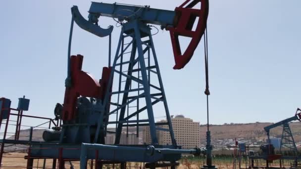 Oil pumpjacks in a working oil field in Baku, Azerbaijan.Silhouette of working oil pump on a background of blue sky and clouds.Oil fields — Stock Video