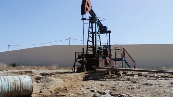 Pompe petrolifere in un giacimento petrolifero funzionante a Baku, Azerbaigian. Silhouette della pompa dell'olio funzionante e un vecchio barile di ferro arrugginito vicino su uno sfondo di cielo blu e nuvole — Video Stock