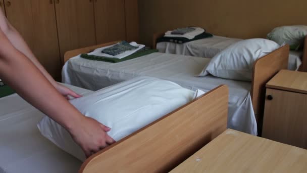 Женские руки бьют подушку в комнате со многими кроватями, избивая подушки — стоковое видео