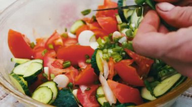 Bahçedeki masada domates, armut ve yeşillik salatası var. El salata keser. Sağlıklı bir salata sebze. Evin dışında piknik.