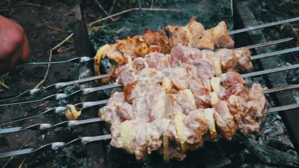 Вкусное сочное жареное мясо на шампуре, только что приготовленное на гриле. Отдых, еда и напитки, люди и праздничная концепция - приготовление мяса на гриле барбекю — стоковое видео