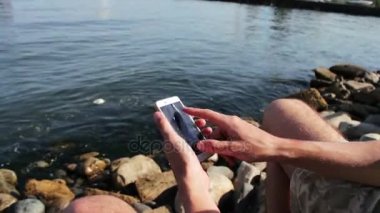 Eller genç bir adam bir şey bir smartphone cep telefonu ile Hazar denizin dalgaları zemin karşı yazın