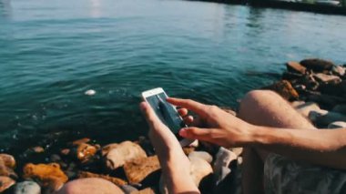 Eller genç bir adam bir şey bir smartphone cep telefonu ile Hazar denizin dalgaları zemin karşı yazın