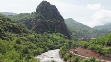 Yeşillik ve yakındaki acele nehir boğulma Kafkasya, keyifli görkemli dağlar. Ermenistan'ın dağlık manzara. Bir traktör dağlık bir alanda yeni rota atarken