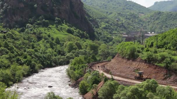 Herrliche herrliche Berge des Kaukasus, im Grünen ertrinkend, und der nahegelegene rauschende Fluss. bergige Landschaft von Armenien. Traktor verlegt neue Route in bergigem Gebiet — Stockvideo