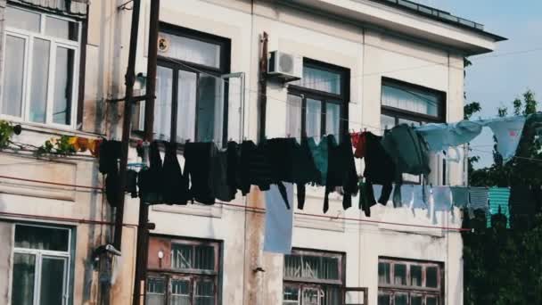 Large number of washed laundry hangs on a rope and dries on the street near the house — Stock Video