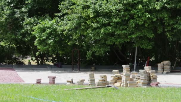 Чоловіки відкладають декоративну різнокольорову тротуарну плитку в дитячому парку. Працівник закладає кам'яну тротуарну плиту. Покласти кольорову плитку в міський парк. Ручна фіксована тесельована тротуарна плитка — стокове відео