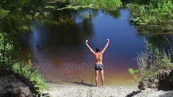 Homme mince faisant des exercices sur la rive de la rivière sauvage — Video