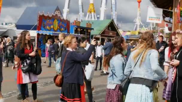 September 17, 2017 - Munich, Germany:Crowd of people in national Bavarian suits Dirdl and Lederhose are walking along streets of Teresienvise near attractions and trays with food and sweets — Stock Video