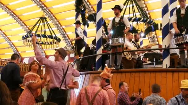 17 de setembro de 2017 Munique, Alemanha: Bem vestidos com trajes nacionais da Baviera, os homens tocam bateria e entretêm a multidão de pessoas que celebram e bebem. em Lowenbreu Barraca de cerveja . — Vídeo de Stock