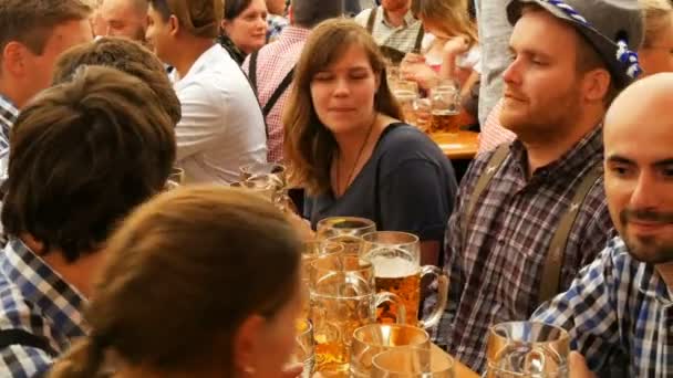 17 сентября 2017 - Мюнхен, Германия: Всемирно известный фестиваль пива Октоберфест, люди сидят в пабе или пивной палатке, пьют пиво с пекарями, смеются, веселятся и празднуют — стоковое видео