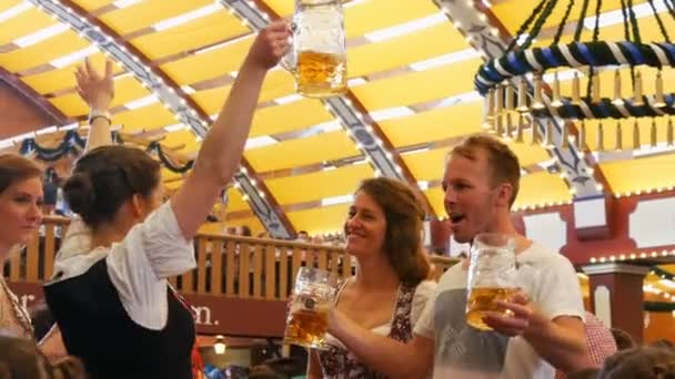 17 de setembro de 2017 Munique, Alemanha: Festival Mundial da cerveja Oktoberfest, belos jovens se divertindo, dançando, bebendo cerveja em uma barraca de cerveja no Oktoberfest, Baviera — Vídeo de Stock