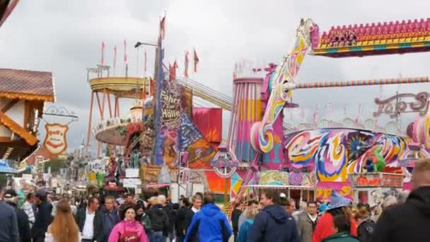 17 de septiembre de 2017 - Munich, Alemania: una multitud de personas vestidas con disfraces nacionales bávaros caminan a lo largo del Oktoberfest pasando por atracciones de entretenimiento y tiendas de campaña con comida y dulces — Vídeo de stock