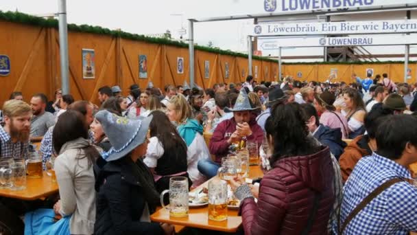 17 september 2017 - München, Tyskland: ungdomar sitter och firar i beergarten på festivalen världen bayersk Oktoberfest. Folk dricker öl från stort glas glasögon — Stockvideo