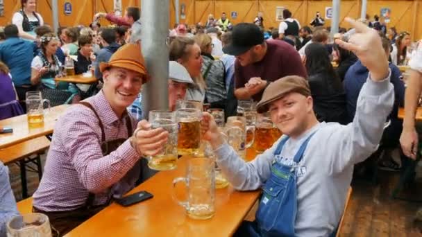 17. září 2017 - Mnichov, Německo: společnost mladých lidí, veselé se odpočívá v beergarten a pití piva z velké hrnky na Oktoberfestu v Bavorsku — Stock video