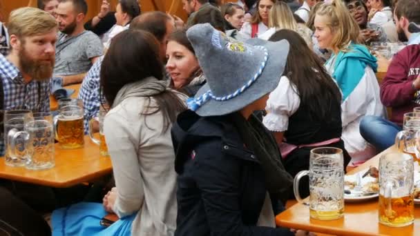 17 de septiembre de 2017 - Múnich, Alemania: los jóvenes se sientan y celebran en el beergarten en el festival mundial de Baviera Oktoberfest. La gente bebe cerveza de tazas de vidrio grandes — Vídeo de stock