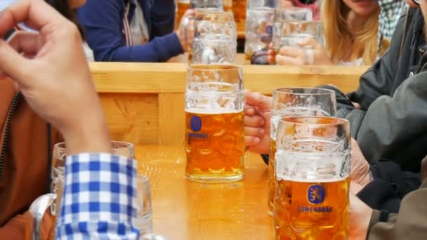 17 września 2017 - Monachium, Niemcy: Młodzi ludzie siedzą i świętować w beergarten na świecie bawarskiej festiwalu Oktoberfest. Ludzie piją piwo z dużych szklanych kubków — Wideo stockowe