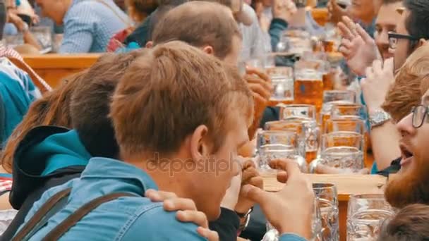 17 de setembro de 2017 - Oktoberfest, Munique, Alemanha: pessoas descansando, rindo se divertindo e sentando bebendo cerveja de enormes canecas de vidro em Theresienwiese, na Baviera, no Festival Mundial de Cerveja — Vídeo de Stock